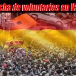 Multitud de voluntarios en el centro de la imagen, con la bandera española difuminada al fondo; en la parte superior, se pueden ver autos volcados; encabezado dice 'Avalancha de voluntarios en Valencia'.